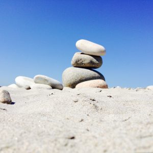 photo of several rocks stacked upon one another on the sand